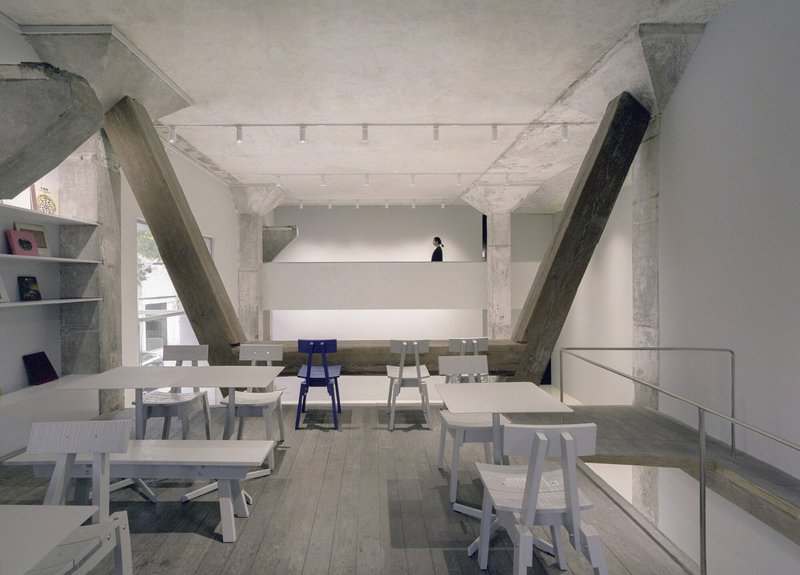 Dining area with exposed concrete columns and diagonal timber braces beneath a coffered ceiling