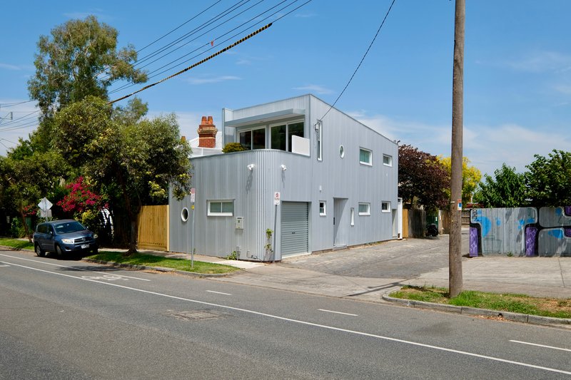 Street view of the two-storey corrugated metal volume with rooftop terrace and chimney