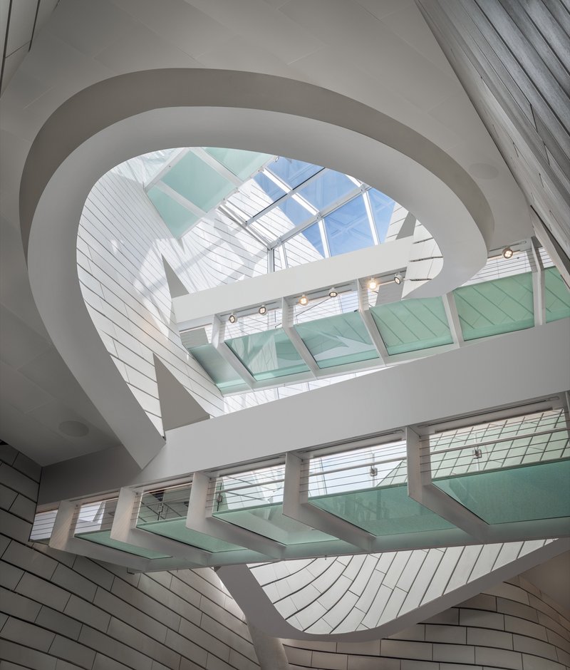 Interior atrium with spiraling white balconies, glass bridges, and skylight flooding the space with daylight