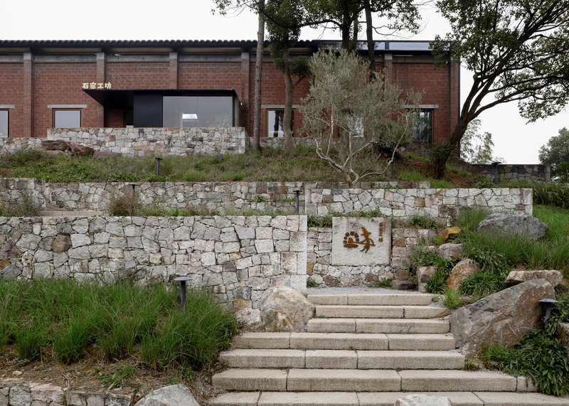 Stone stairs ascending through terraced dry-stone retaining walls with grasses and trees
