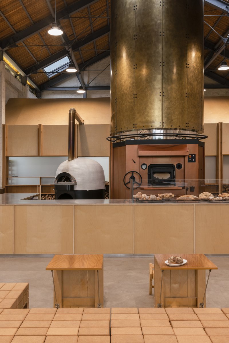 Bakery workspace with white-tiled dome oven, copper deck oven and brass flue under timber ceiling