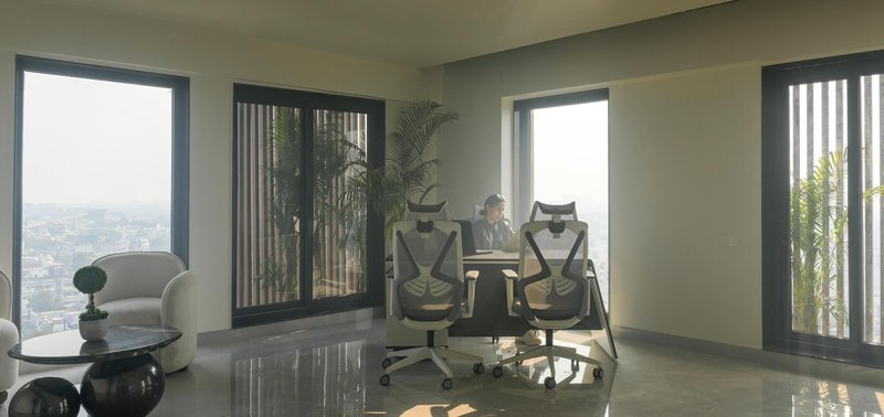 Interior workspace with glass doors opening to terracotta-screened balconies overlooking the cityscape