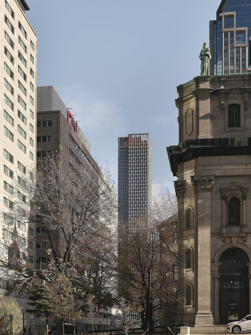Street view of the tower framed between bare winter trees and a historic stone church