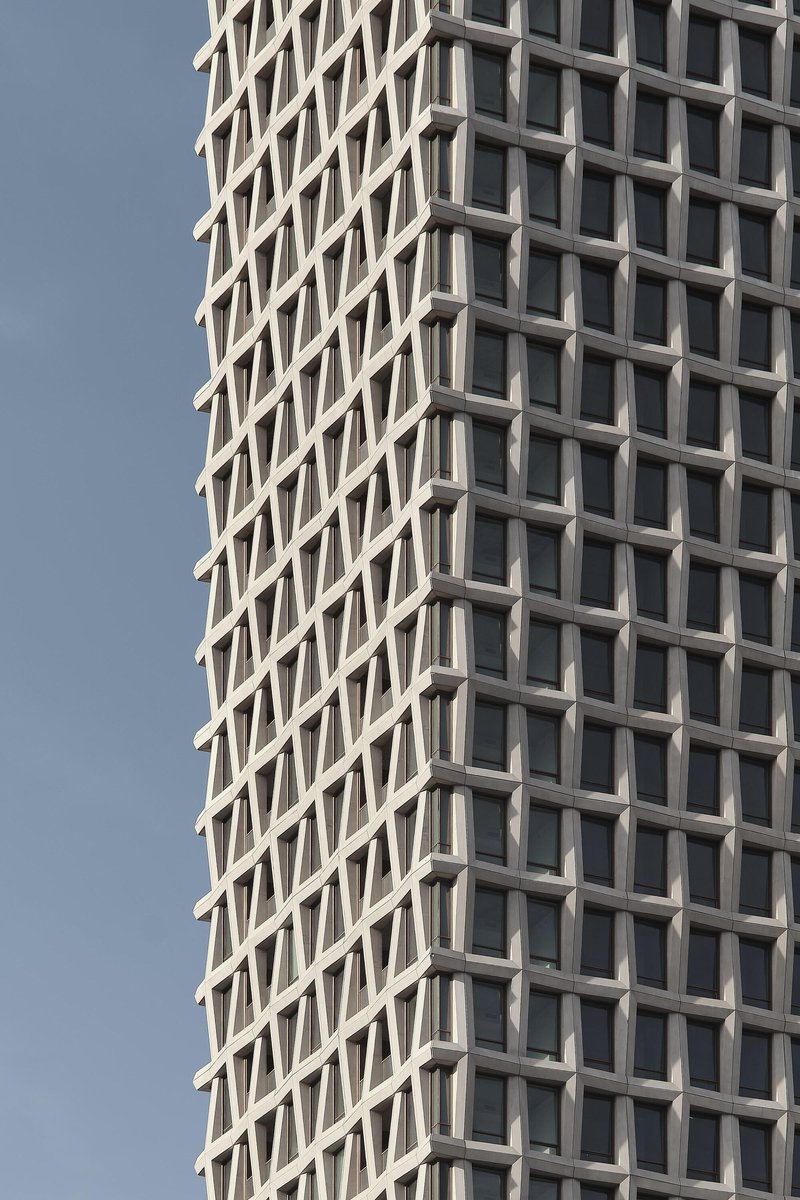 Close-up of the diagonal grid window pattern created by angled concrete mullions