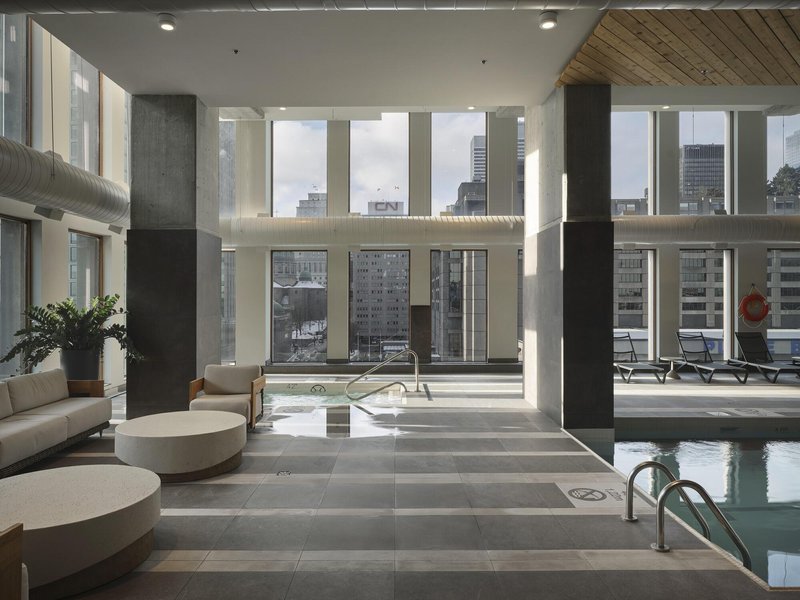 Double-height indoor pool area with concrete columns, wood ceiling and floor-to-ceiling glazing