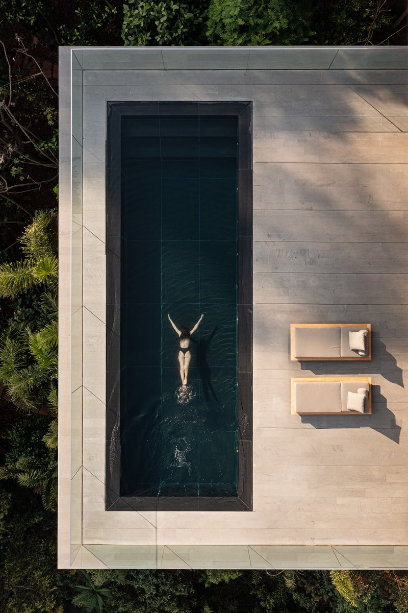 Aerial view of lap pool with swimmer and two lounge chairs on limestone paving