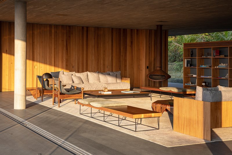 Covered lounge with freestanding fireplace and vertical timber cladding in golden afternoon sun