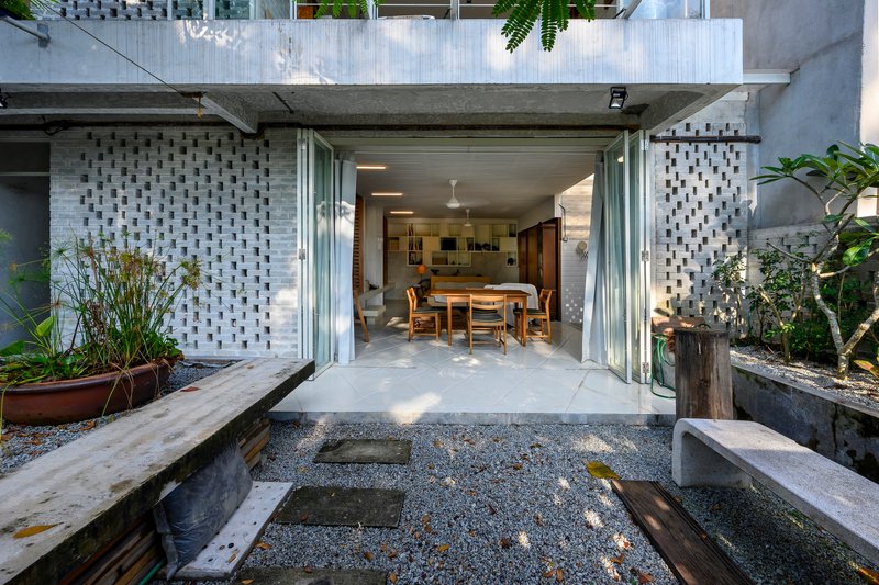 Ground-level courtyard opening to dining room through folding glass doors with gravel garden and concrete benches