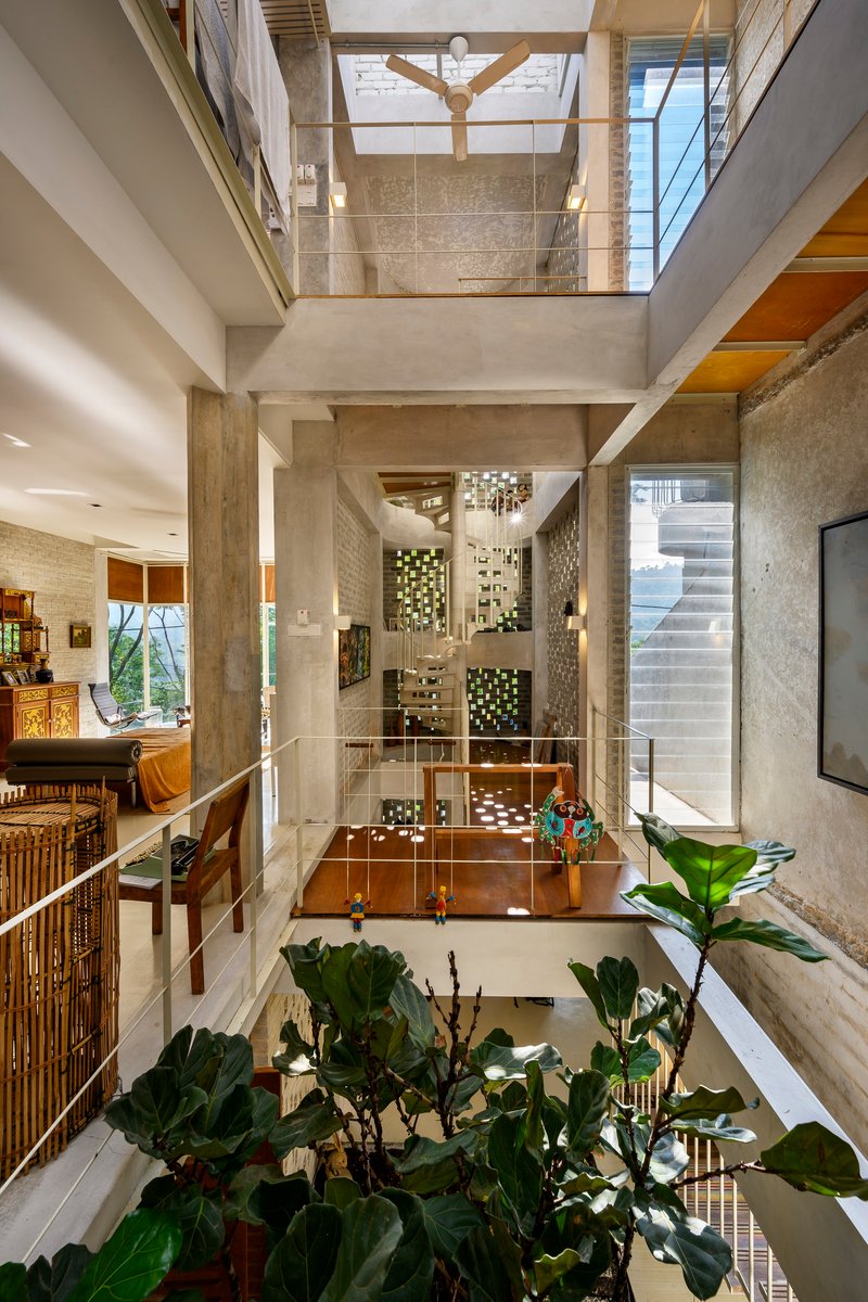 Triple-height atrium with concrete columns, exposed timber beams and planted courtyard below glass bridges
