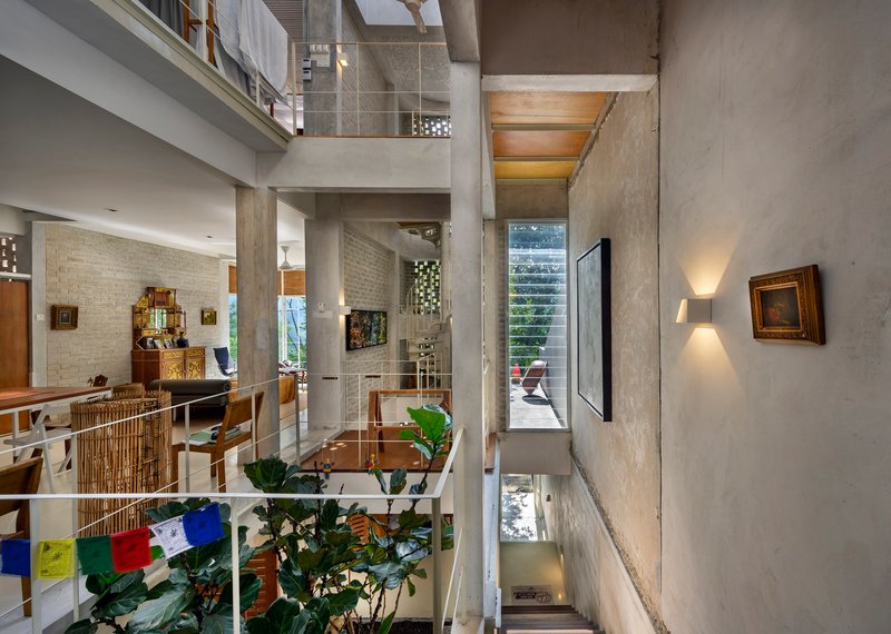 Multi-level interior with exposed concrete columns and mezzanines connected by stairs and planted areas below