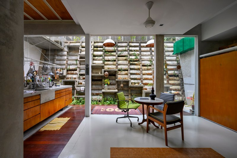 Living space opening to internal courtyard through concrete frame with horizontal louvered planting wall beyond