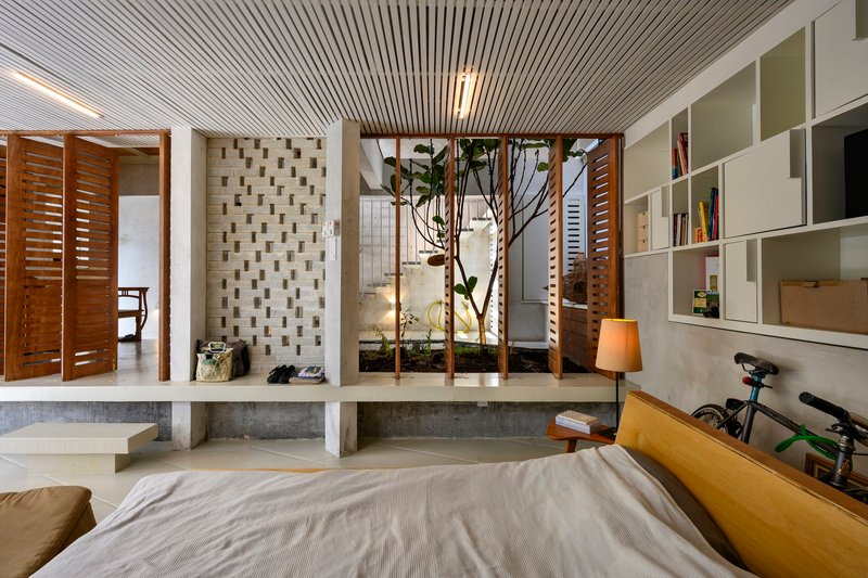 Bedroom with timber slatted ceiling, interior planted courtyard, and white shelving with louvered timber screens