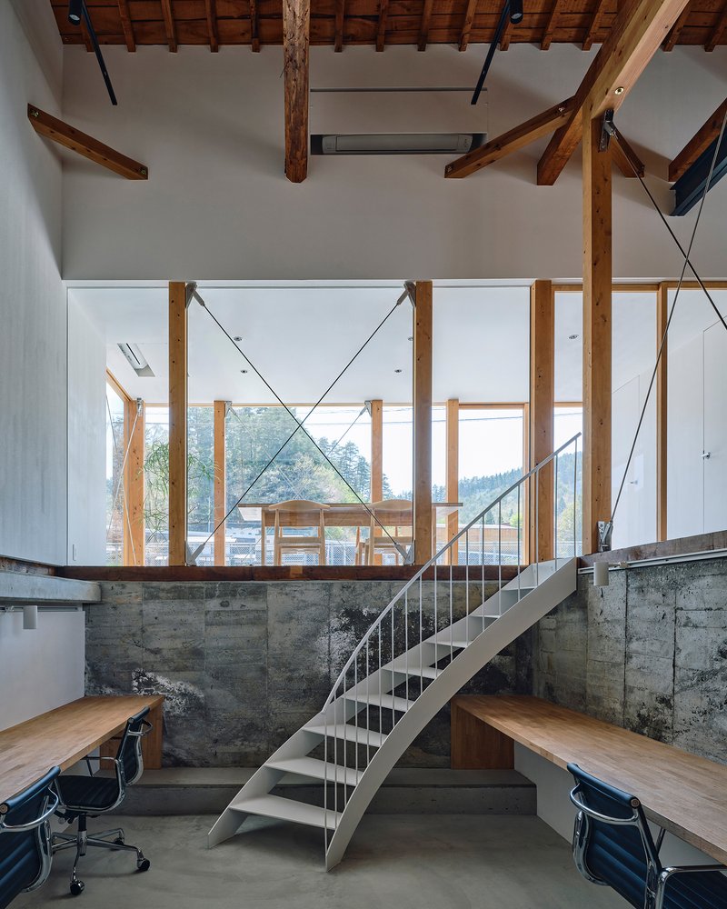 Steel plate staircase rising from a concrete half-wall under timber columns and rafters