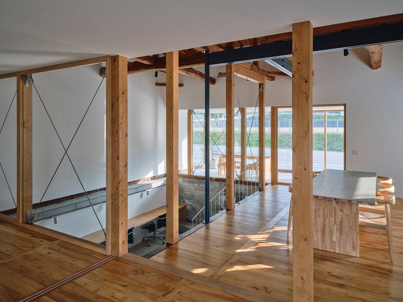 Upper level timber frame and cable bracing surrounding a glazed stairwell opening with table beyond