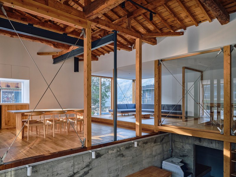 Split-level interior showing exposed timber ceiling structure and concrete base with dining area above