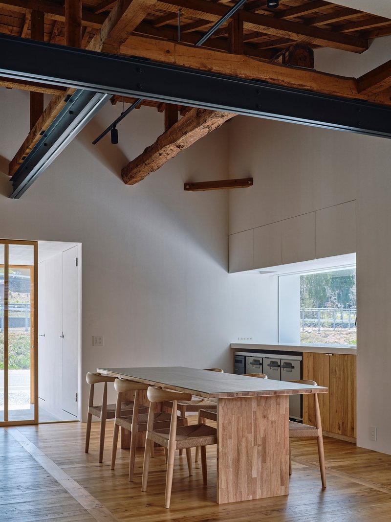 Dining area with exposed timber ceiling beams and a steel structural beam beneath white walls