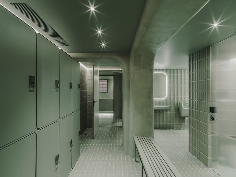 Curved passage connecting locker area to shower rooms with painted green ceiling and mosaic floor
