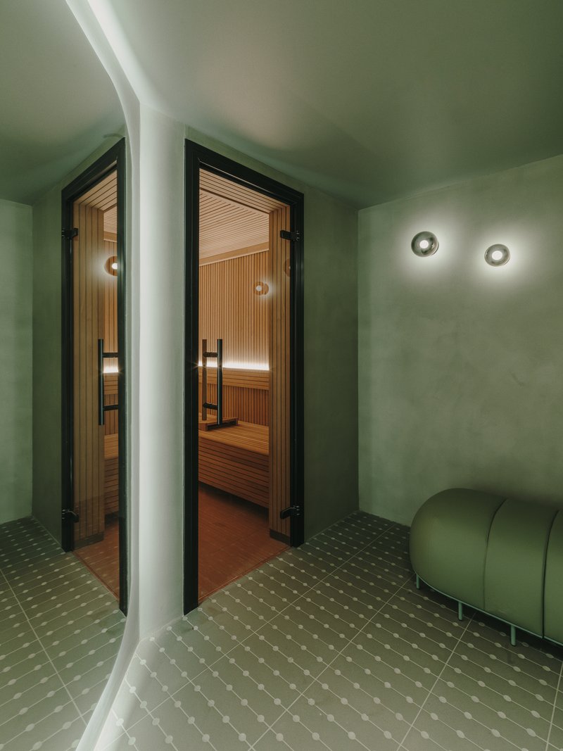 Glass-doored sauna entrance with timber interior visible beyond curved white column