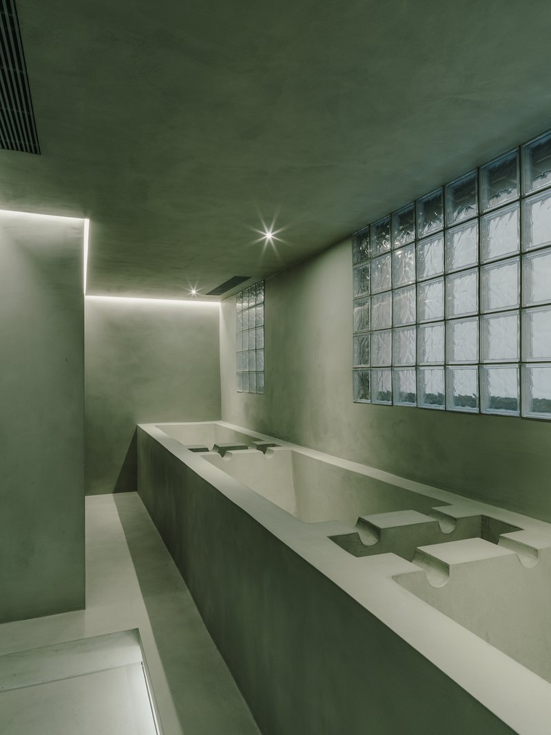 Washroom with integrated basin counter, glass block window wall and concealed ceiling lighting