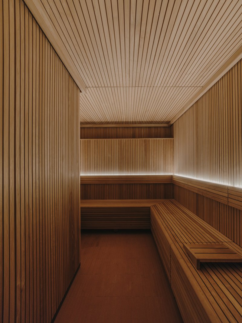 Sauna room lined entirely in vertical wood slats with tiered benches and continuous perimeter lighting