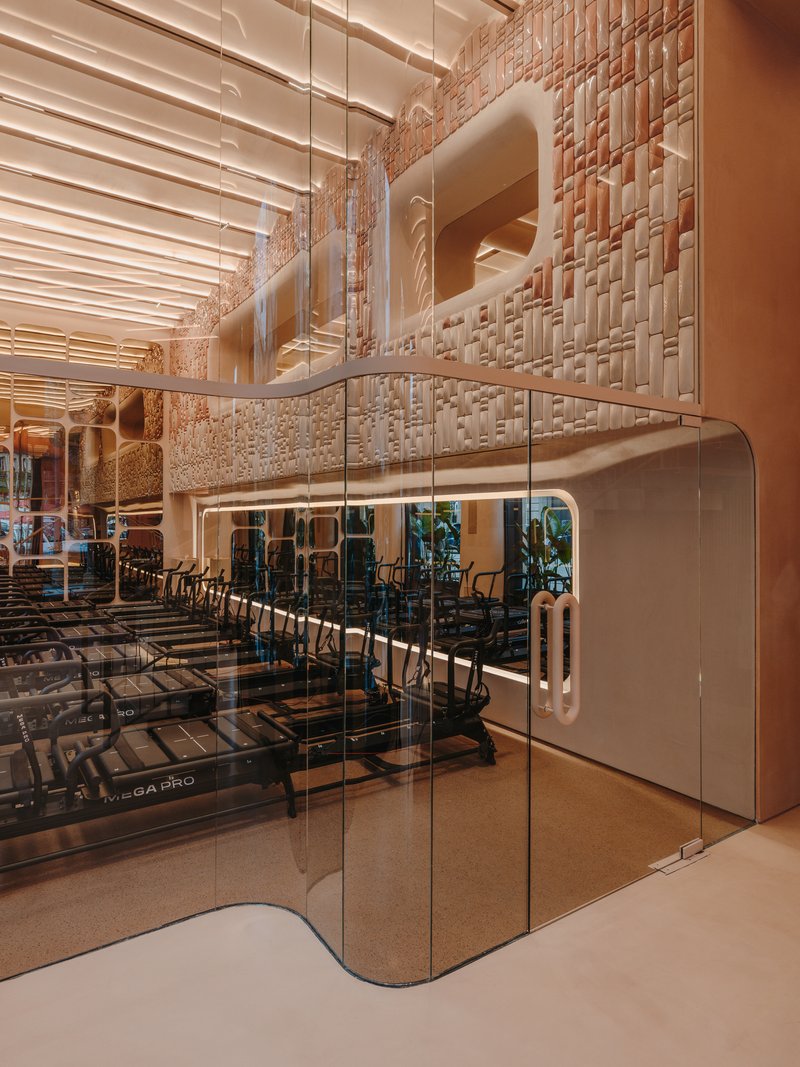 Glass partition separating seating area from double-height space with textured wall panels
