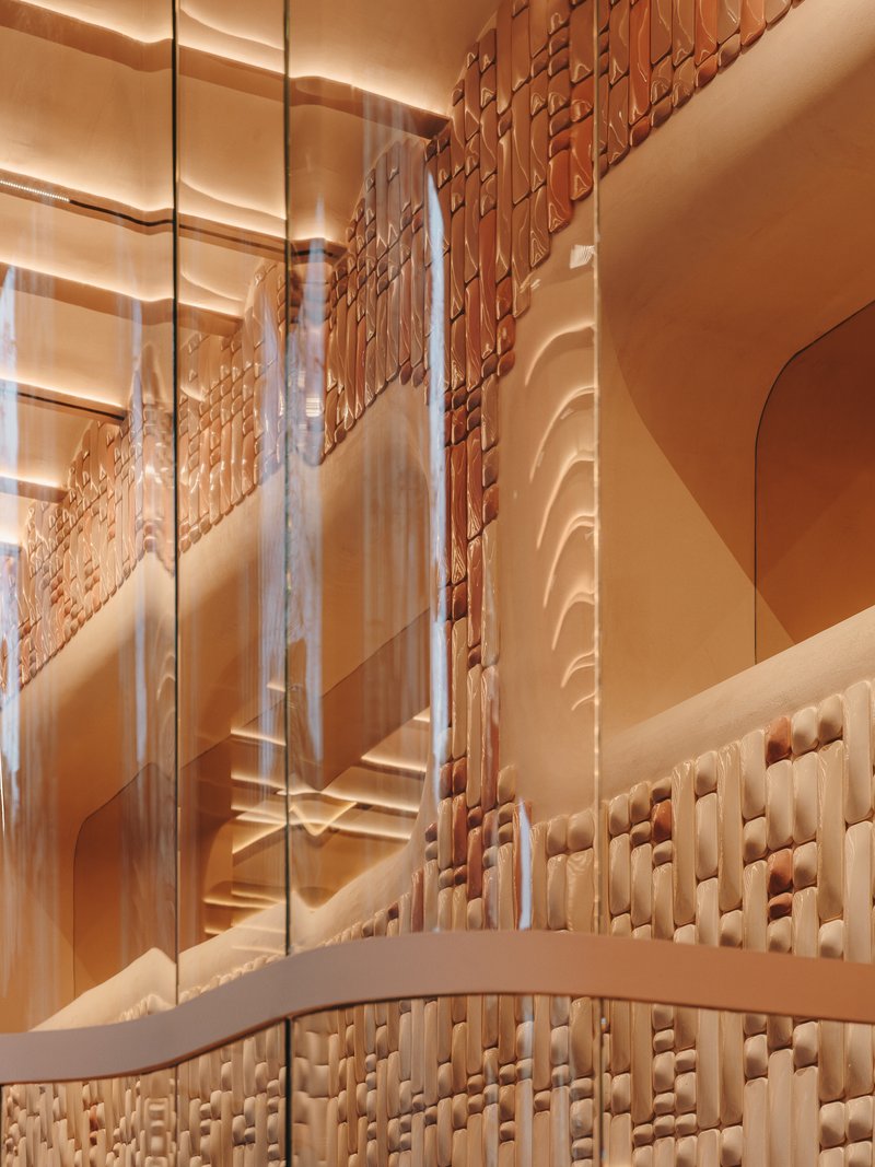 View through glass looking up at layered arched openings and woven terracotta wall surface