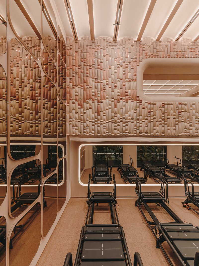 Diagonal timber bracing and basketweave wall above mirrored balcony overlooking Pilates equipment below
