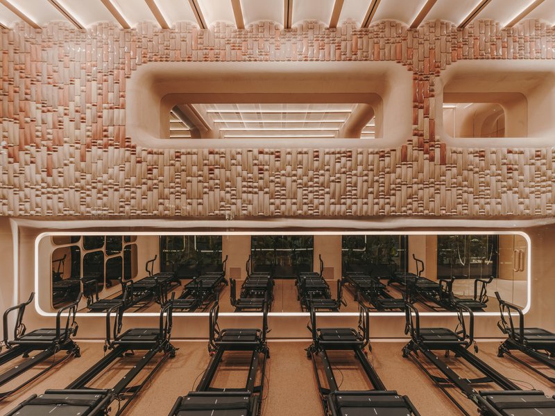 Frontal view of the textured basketweave wall with recessed openings and Pilates reformers on lower level