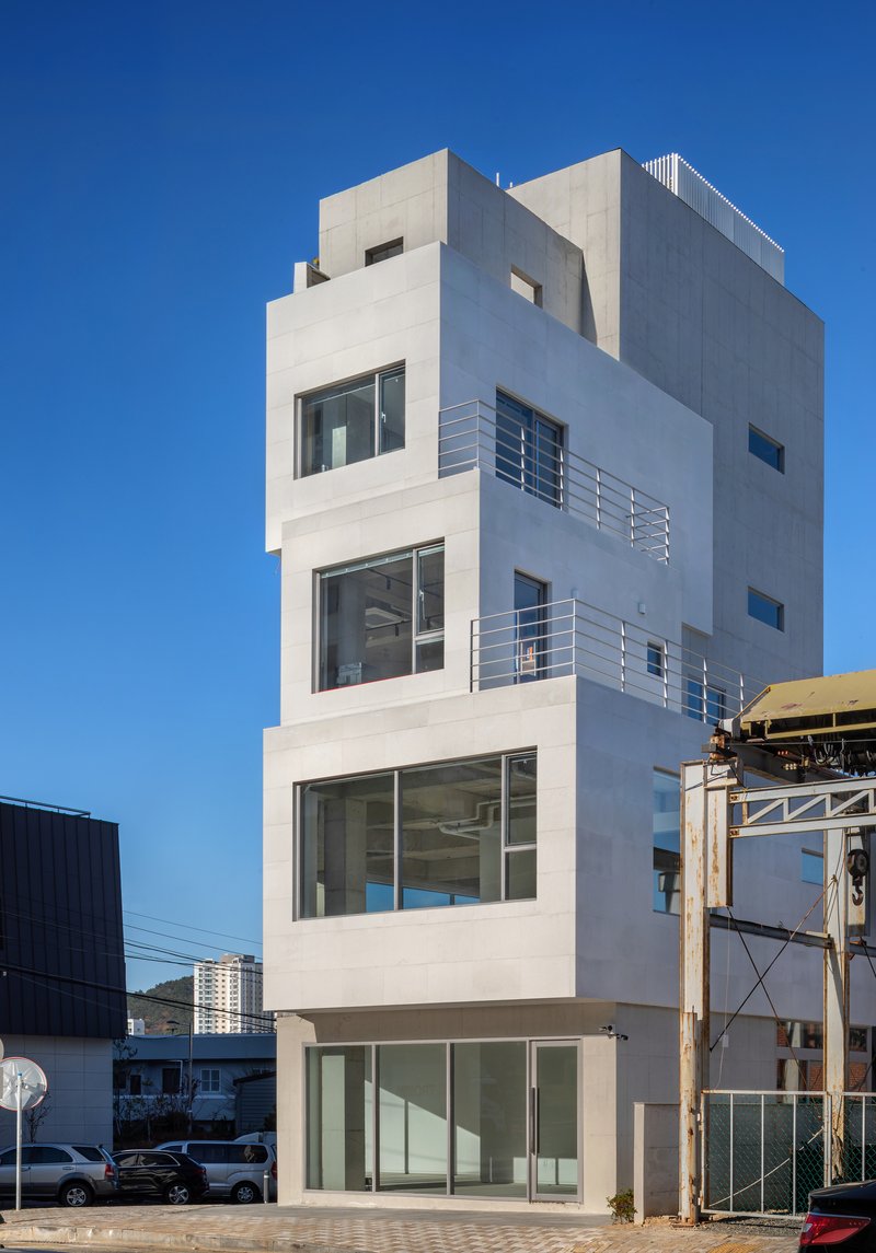 White stucco facade with recessed balconies and two figures standing on upper level railings