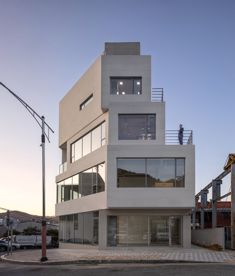 Four-story stucco facade with stacked terraces and full-height glazing at dusk