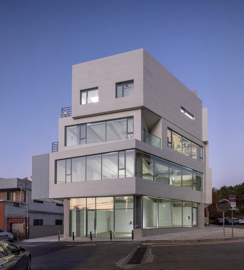 Street corner facade with offset floor plates and illuminated interiors at twilight