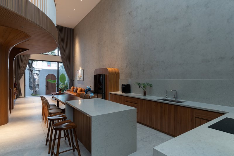 Open kitchen with marble waterfall island looking toward arched windows and planted courtyard at dusk