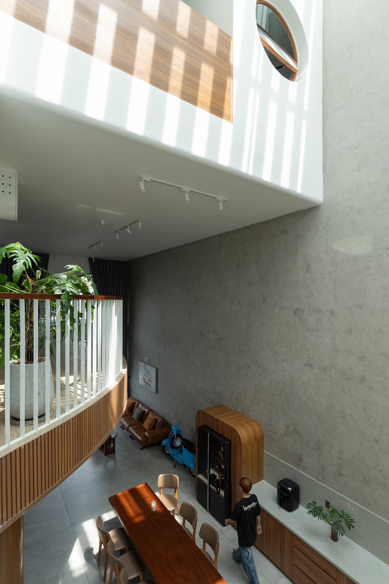View down into the living area showing timber balustrade, concrete walls, and dappled afternoon light