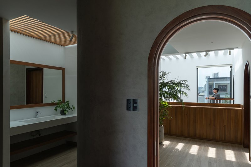 Arched timber doorway framing the wood-paneled kitchen beneath a slatted skylight