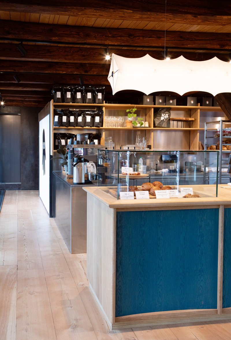 Service counter with display case, blue-stained panels, and open shelving under scalloped fabric pendant