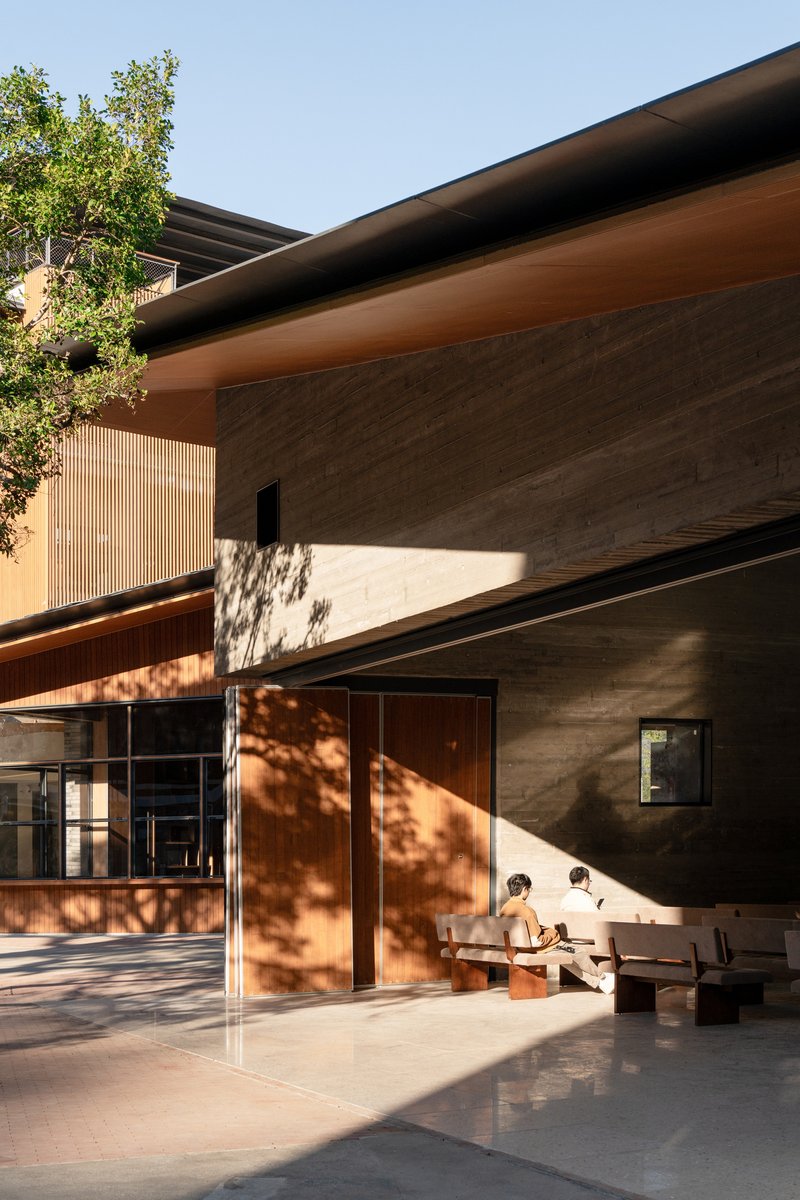 Covered outdoor area with concrete walls and dappled tree shadow falling across timber doors