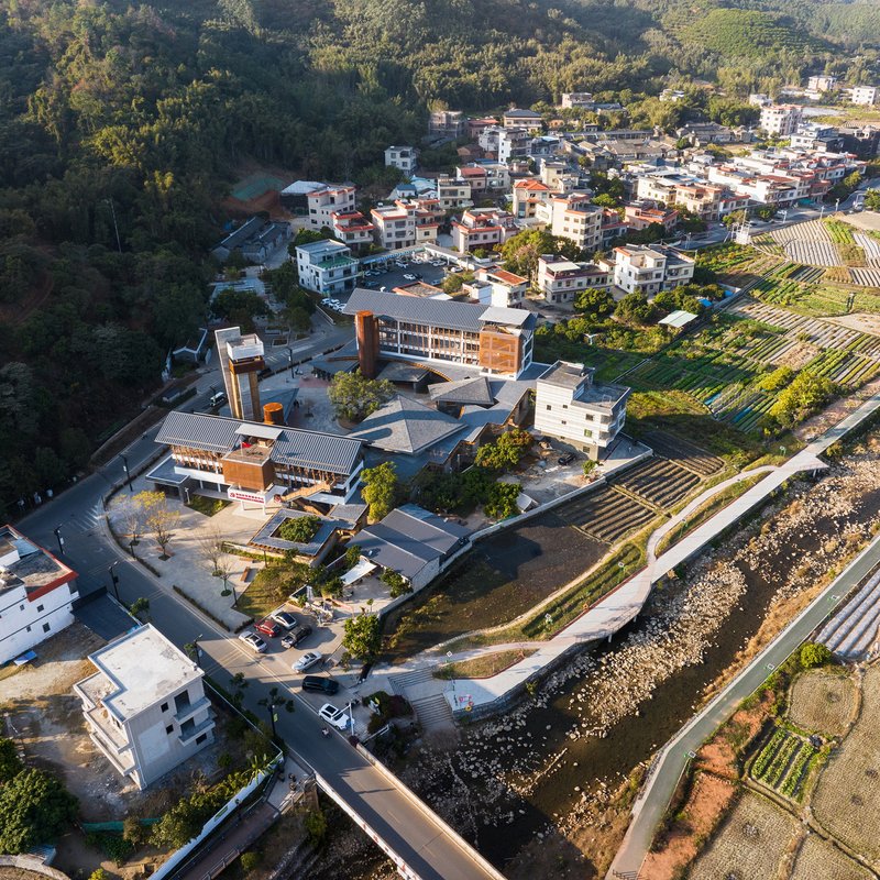 Aerial view of the compound with tower and low roofs nestled between village and agricultural fields