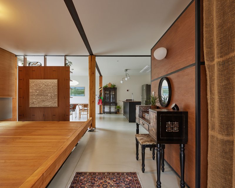 Open living space with timber-clad walls and polished concrete floor connecting kitchen to dining area