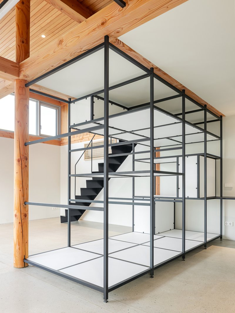 Freestanding black steel frame structure housing floating staircase with glass infill panels