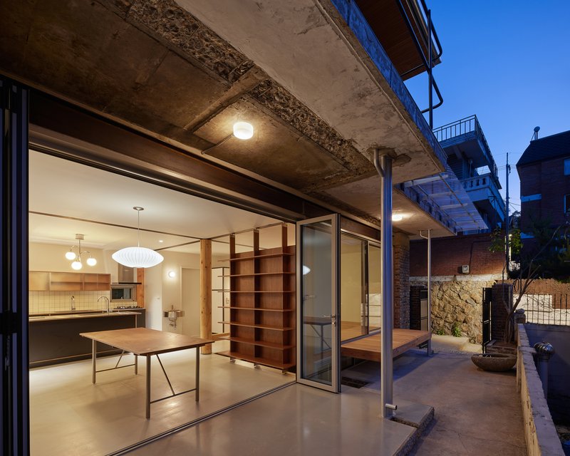 Open sliding glass doors connecting the dining area to the concrete terrace at dusk