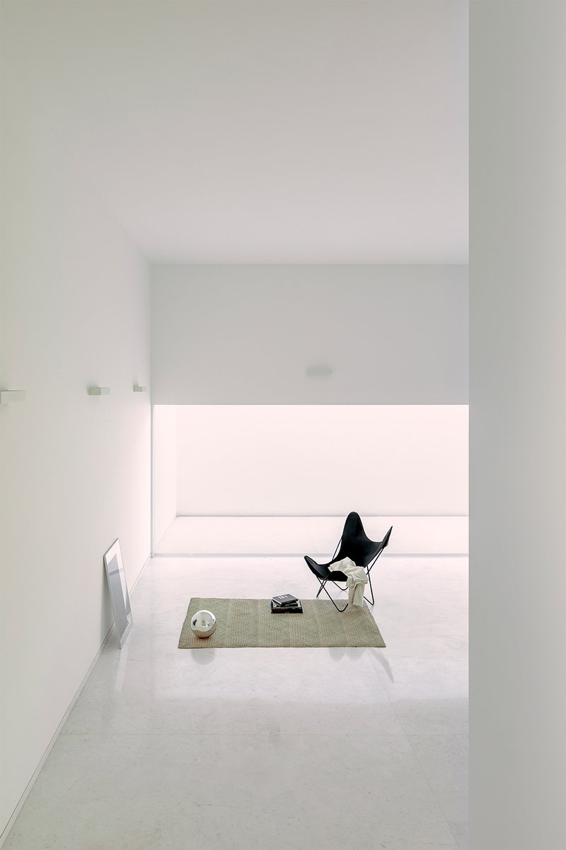 Framed view through doorway to a butterfly chair on a woven rug beneath a horizontal window