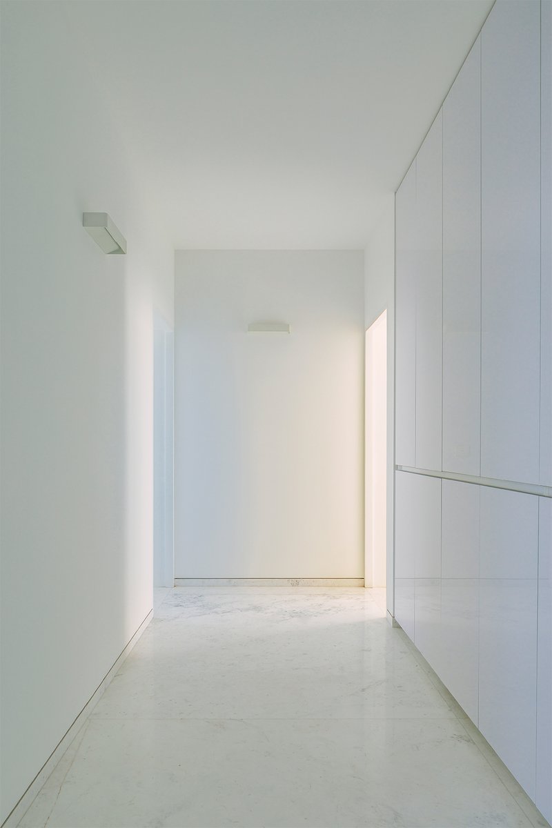 White corridor with built-in cabinetry and polished concrete floor under diffused natural light