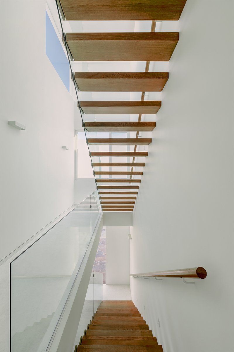 Timber staircase with glass balustrade and floating wooden treads beneath a skylight
