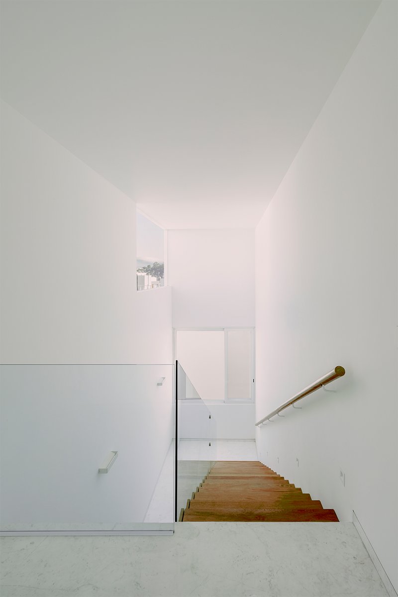 View down the timber staircase with wooden handrail and glimpse of window beyond