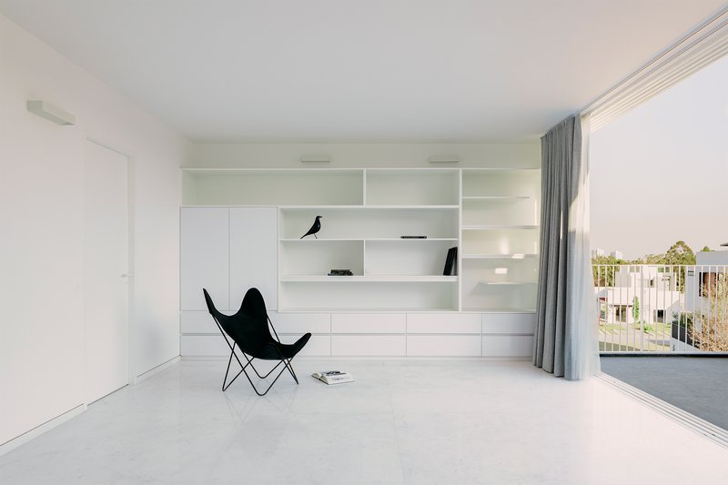 White interior with full-height built-in shelving and butterfly chair beside sliding glass doors