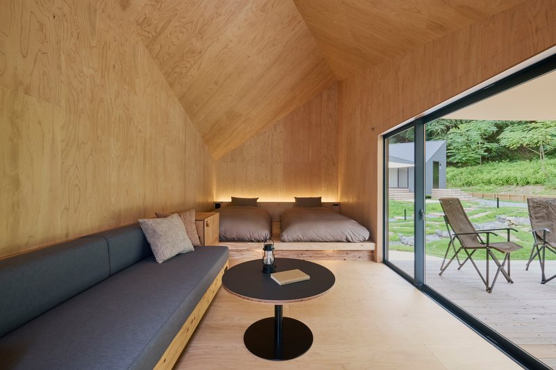 Plywood-lined sleeping loft with built-in platform bed and sliding glass door to deck