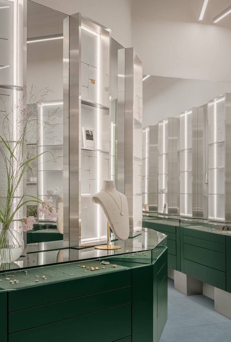 Backlit display shelving and green lacquered jewelry cases reflected in mirror panels