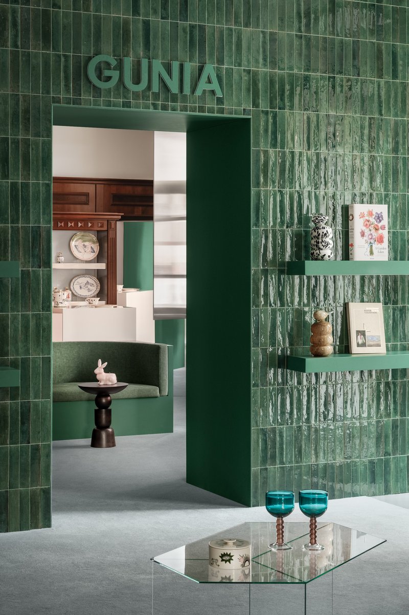 Glazed green ceramic tile wall with integrated shelving and doorway framing view to adjacent room