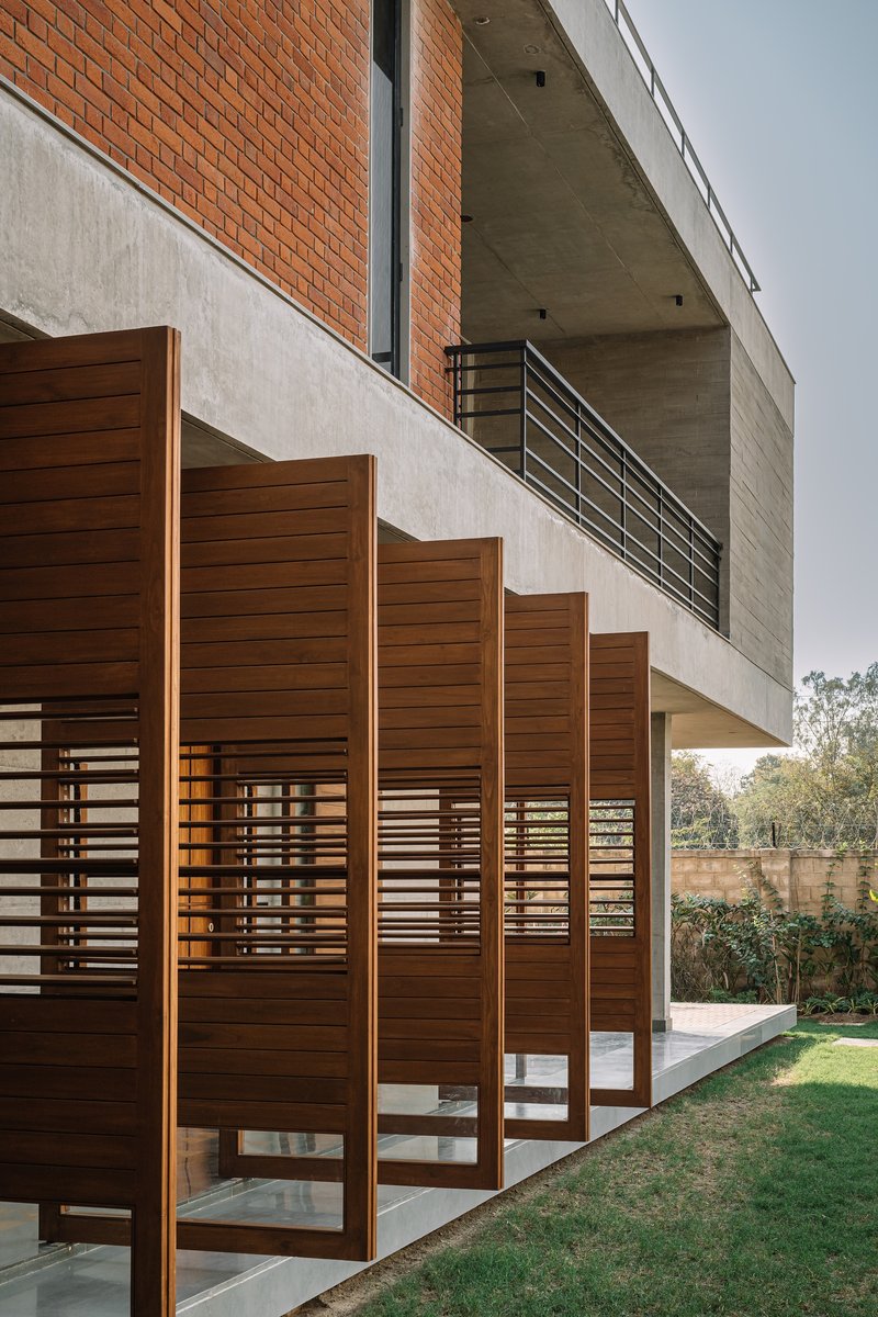 Angled timber louver panels pivoting open along the garden terrace under overcast sky