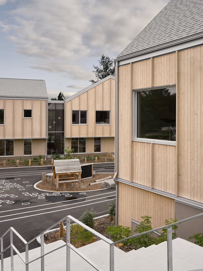 Elevated view of timber gables surrounding a patterned courtyard with planted beds and a timber bench